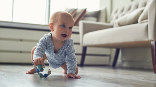 Kleines Baby mit einem Greifspielzeug für Babys in der Hand.